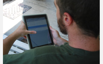 Photo of a researcher recording homeowner responses to questions on a tablet computer.