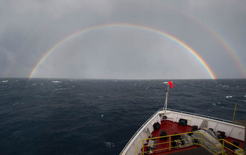View of ocean horizon and rainbow from bow of research vessel.