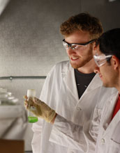 Photo of researchers examining a flask of cyanobacteria.