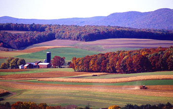 a farm and forests in midst of fall color change.