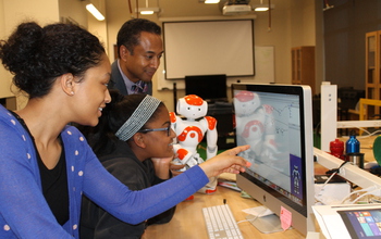 Photo of Andrew Williams instructing girls using the Choreographe visual programming environment