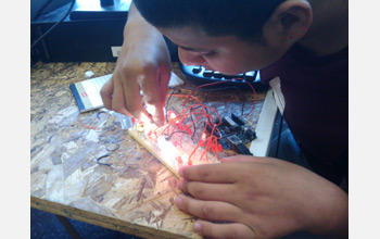 Photo of a student experimenting with using an Arduino microcontroller to power LEDs.