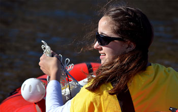Photo of student Marisa LaRouche sampling water in a Greenland lake.