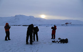 an ice auger is used to drill a borehole through Isortoq River