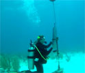 researcher under water holding a recording device.