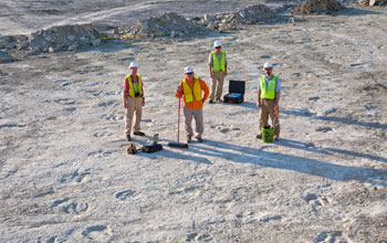 Researchers stand amid a field of dinosaur tracks in Arkansas