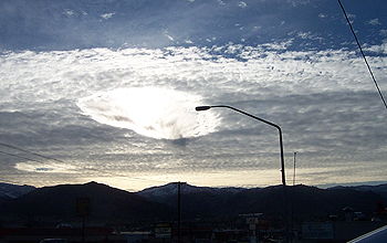 Hole-punch clouds seem to touch a streetlight in Washington State.