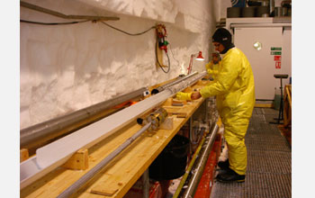Photo of a person pushing an ice core out of the drill.