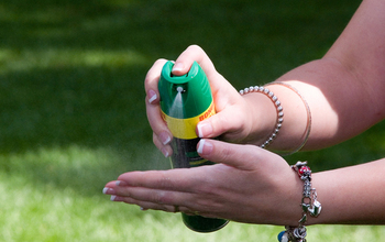 person spraying insect repellant on hands