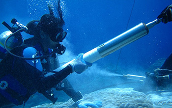 Scientists retrieve a coral core piece during an underwater drilling process.