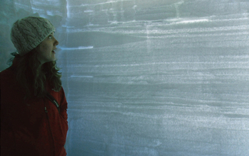 Kaitlin Keegan in a snow pit on the Greenland ice sheet. The pit shows layers of accumulation.