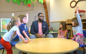 children sitting around a table with a man