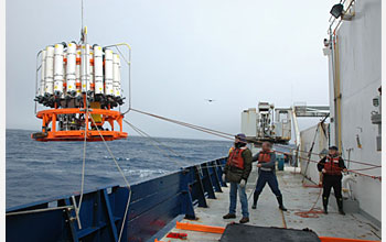 Photo of 3 crew members, "tag lines" and equipment on the ship's deck.