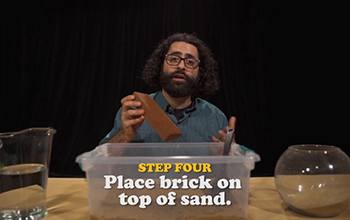 Man holding brick over sand in container