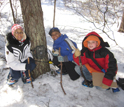 Three young ecology students with a "camera trap" in the woods.