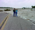 two people standing next to a flooded highway in Louisiana.