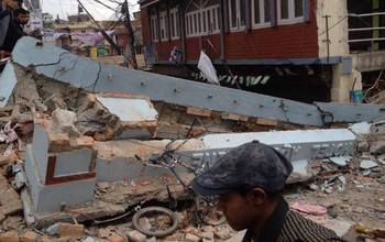 man by rubble and damaged houses after the April 2015 earthquake in Nepal