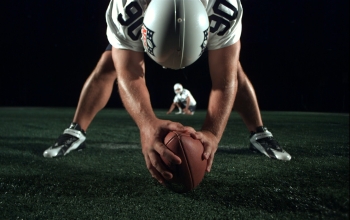 Football player holding football on ground and looking behind