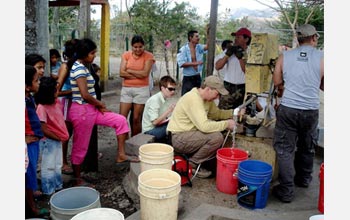 Photo of John Gierke measuring the water level, with people and buckets around him