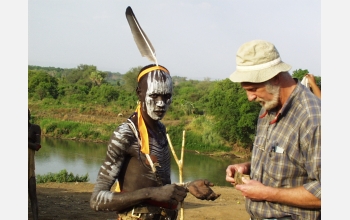 Frank Brown and a Mursi warrior examine a sample of colored rock.