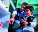 An EPICS student showing a child with a disability how to utilize a unique dollhouse