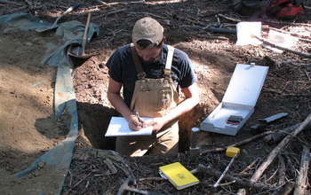 Patch of ground in the Pacific Northwest, with scientist making soil analyses.