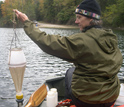 A water sample is collected from a rowboat using a plankton net.