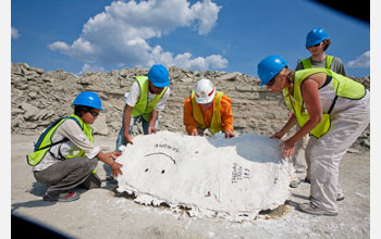 Researchers lift a dried plaster cast containing the prints of two dinosaurs