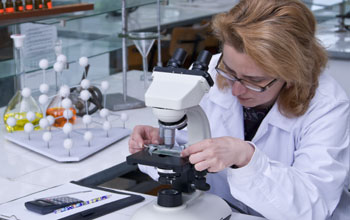 Photo of a scientist working with a microscope in a lab