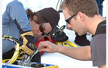 Photo shows Gretchen Hofmann and Tom Crombia carrying out a "field repair" on the rover.