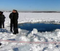 People standing next to hole in the ice at Russia's Lake Chebarkul, said to be caused by the meteor.