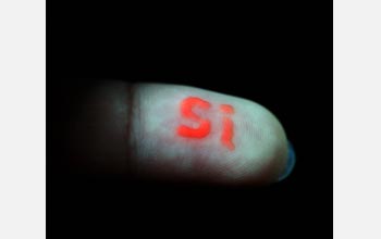 Photo of silicon element symbol spelled out on a fingertip with luminescent silicon nanoparticles.
