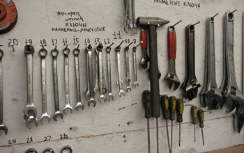Photo of a wallboard with hanging tools with descriptions in Russian and English at Lake E site.