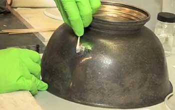 Hands polishing tarnished silver bowl