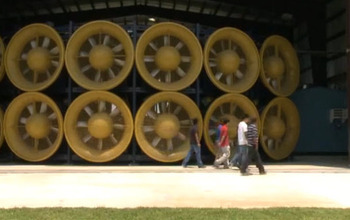 Four students walking in front of giant fans