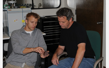 Photo: Scientists Noah Plavansky and Tim Lyons discuss attributes of a banded iron formation sample.