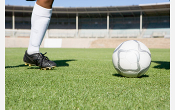 Photo showing the leg of a soccer player and a soccer ball.