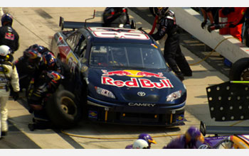 Photo of the Red Bull pit crew changing tires during a pit stop.