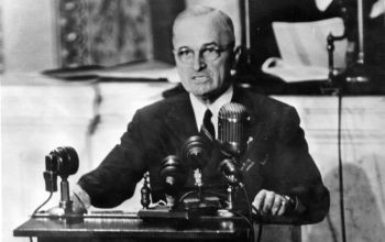 harry s truman standing in front of microphones