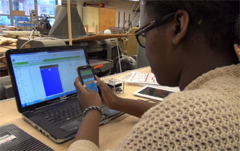 student looking at a smart phone and computer screen