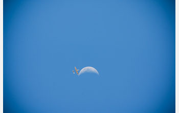 Photo of  AUAV involved in the Maldives project flying by the moon in a blue sky.