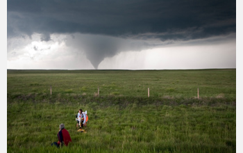 Photo of researchers studying a tornado from a safe distance away.