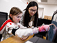 student Di Wu directs a volunteer as she touches images on a screen using a device