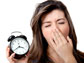 a lady yawning while holding a clock