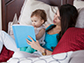 a mother and child in bed reading a book