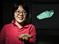 Wu-Jung Lee holds a skull of an Egyptian fruit bat; on the screen is the 3-D mesh of a fruit bat's head