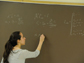 a student writes equations on blackboard