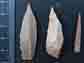 two stone tool points and a bone point or needle
